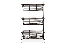 The nkuku Inkollu Three Tier Storage Stand in antiqued brass has rectangular open-wire baskets stacked vertically on a minimalist frame with four slender legs, ideal for kitchen organization and storage.