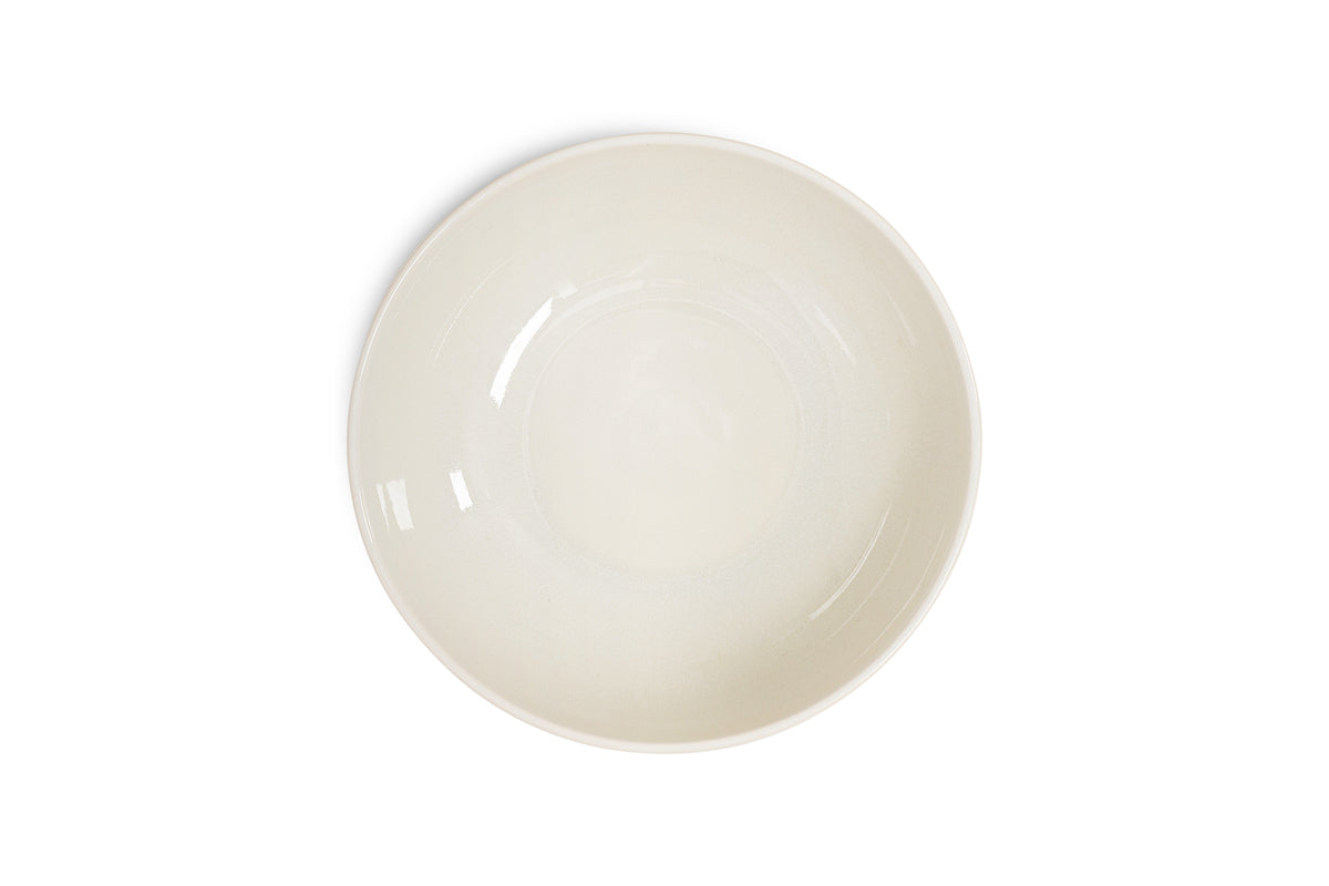 The Edo Pasta Bowl - Terracotta by nkuku is displayed centered on a white background. Its off-white ceramic has a smooth, glossy finish and minimalist, unadorned design, showcasing light reflections for an elegant look.