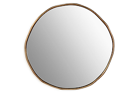 The nkuku Mchanga Organic Shape Mirror features a round, irregular shape with a thin antique brass frame. Its smooth, clear surface and minimalist design give this wall mirror a modern artistic look against a plain white background.