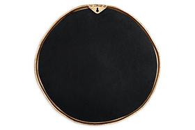 The nkuku Mchanga Organic Shape Mirror features a round, irregular black design with a slim antique brass border, a keyhole hanger at the top, and a smooth, subtle matte surface—all set against a white background.