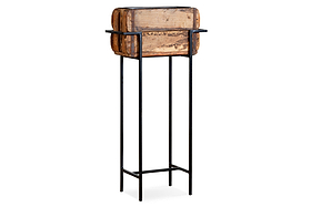 The nkuku Amazzi Indoor Planter Stand – Natural & Black features a rustic rectangular reclaimed wooden planter atop a tall black metal frame, blending vintage charm with modern style for an elegant indoor plant display.