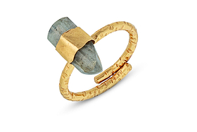 The Darti Labradorite Ring by nkuku features a textured gold-plated open band that elegantly holds a large, pointed gray labradorite stone in a rough, matte setting. With uneven shapes and a rustic finish, both the ring and the stone showcase an ancient, handcrafted aesthetic that highlights the piece’s bold design. The product is photographed against a white background.