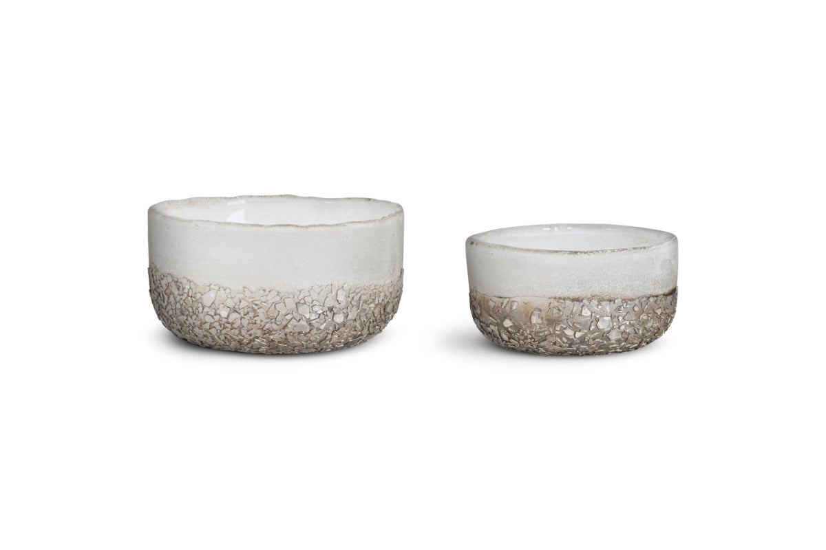 A set of two Riyara Recycled Glass Tealights in Silver Sparkle by nkuku is displayed against a plain white background. Reminiscent of minimalist tealight holders, these simple, round pieces vary in size—the one on the left is larger and taller, while the right is smaller and shorter. Each tealight features a subtle texture with a shimmering silver finish.