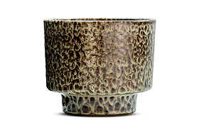 The Uzuri Planter - Brown - Wide by nkuku features a textured, mottled brown and beige ceramic glaze. Its surface showcases raised, irregular patterns reminiscent of tree bark, lending it the earthy charm of a sculptural piece. With straight sides, a slightly flared rim, and a narrow cylindrical base, the planter is displayed against a plain white background.