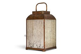The nkuku Ruala Lantern - Brass & Clear features a vintage-inspired square design with a rusted brass finish, ribbed glass panels, and an aged appearance reminiscent of candlelit evenings. It includes a hinged door with a small latch on one side and a curved handle on top, and is photographed on a flat white background.