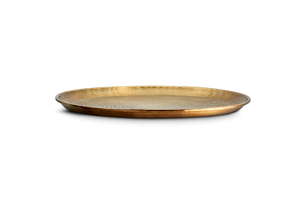 The Amai Etched Round Tray by nkuku, crafted from brass, features a round, shallow design with a beautifully textured, hammered surface. Centered on a white background, this decorative serving tray boasts a slightly raised rim and warm golden-brown tones that lend it a rustic, handcrafted charm.