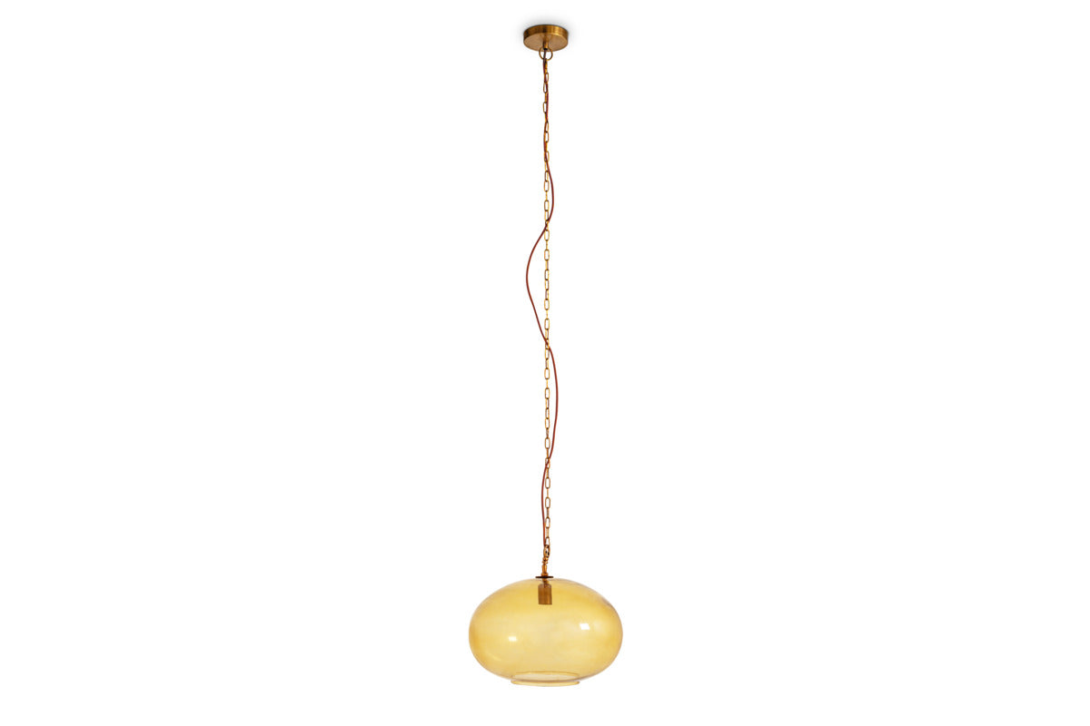 The large, round Otoro Recycled Glass Pendant in Honey by nkuku features a glossy, spherical yellowish-amber shade crafted from recycled glass. Suspended from a long, slender chain and cord connected to a circular ceiling mount, the pendant is finished with a metallic brass fitting cap at the top and has a small opening at the bottom.