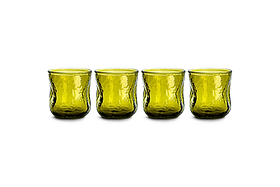 A set of four nkuku Chandani Tumbler - Green - Short glasses, each featuring a subtly tapered shape and textured hammered surface, are arranged in a row on a white background. This handmade glassware boasts a modern design with a translucent finish.