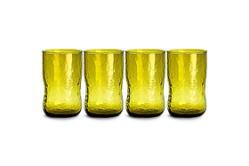 Four Chandani Tumbler - Green - Large glasses from nkuku, with a yellow-green tint and slightly textured, wavy surface, stand side by side in a row on a white background. Each cylindrical glass in this set of four showcases subtle irregularities in shape, reflecting the unique charm of handmade glassware.