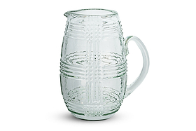The nkuku Kaanch Jug – Clear features a wide-bodied design with a sturdy handle and is crafted from clear glass. Its body showcases an embossed check pattern composed of raised dots and lines, while a small spout adds to its functional charm. The jug is displayed on a plain white background.