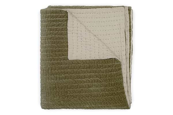 The Nidra Velvet & Linen Bed Quilt - Moss by nkuku is a king size cotton velvet quilt with Kantha quilting, featuring a textured olive green front and smooth beige back. One corner is folded to reveal both sides.