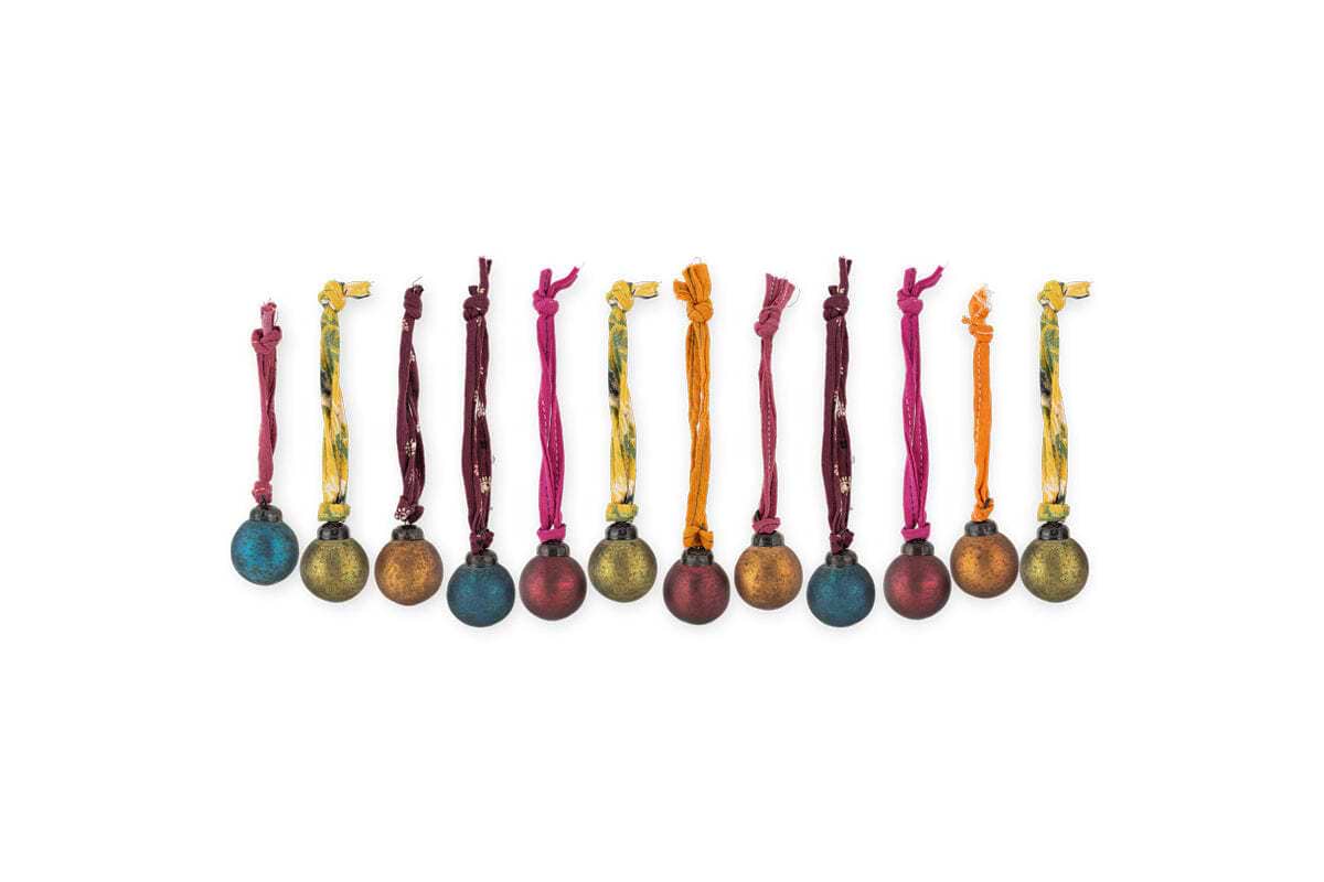 The nkuku Oko Mini Baubles - Mixed Matt (Set of 12) features metallic blue, red, gold, and brown baubles with a rustic matte finish and vibrant hanging ribbons, arranged in a charming festive row against a white background.