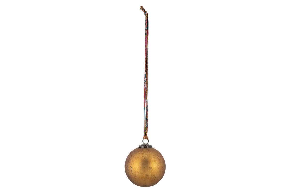 The nkuku Oko Giant Bauble - Matt Gold features a slightly mottled finish and hangs from a vibrant, patterned ribbon, making it a charming addition to festive décor against any plain background.
