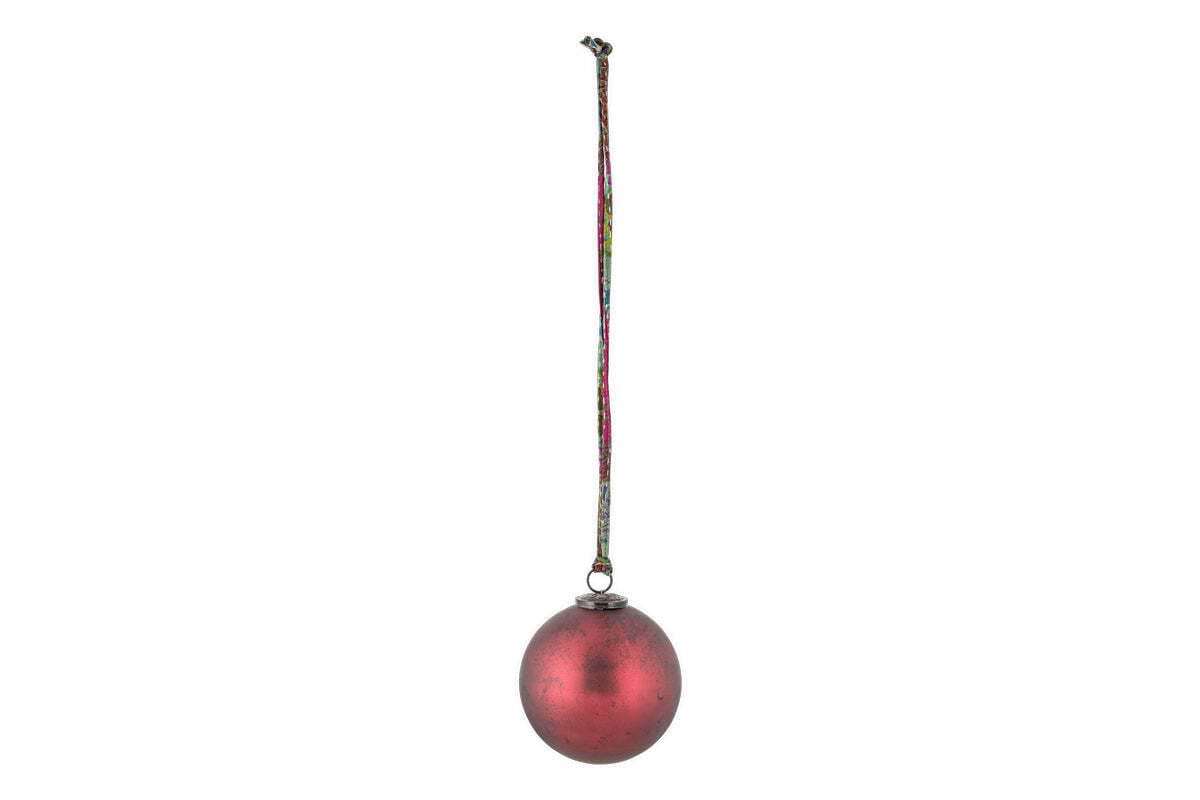 The nkuku Oko Giant Bauble - Matt Bordeaux features a slightly weathered red finish and a small metal cap, hanging from a multicolored string. Its elegant design makes it a charming addition to any festive display.