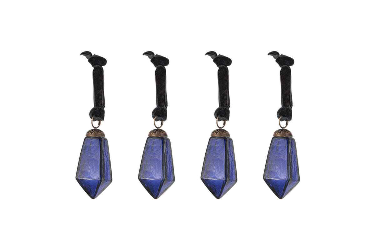 The nkuku Ratnam Baubles - Indigo - Small (Set of 4) feature faceted deep blue crystal points with an antique glass finish on black velvet ribbons. Each ribbon is topped with a black crow figurine for a gothic, elegant look.