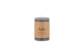 The Rustic Soy Blend Mini Pillar Candle - Charcoal by nkuku is a grey mini pillar candle with a textured finish and a brown label, shown against a white background.