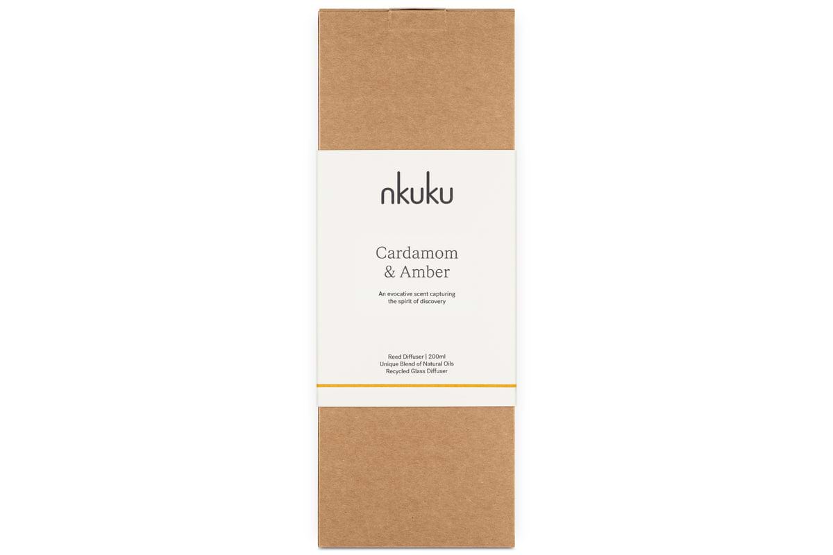 A rectangular brown nkuku box labeled Cardamom & Amber Reed Diffuser with a white band. The 100ml packaging highlights rich amber notes.