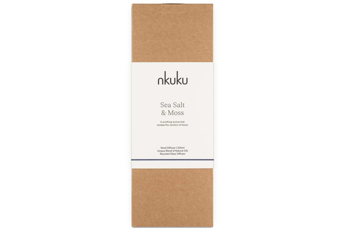 The nkuku Sea Salt & Moss Reed Diffuser comes in a brown rectangular cardboard box with a central white label, featuring minimalist, elegant packaging.