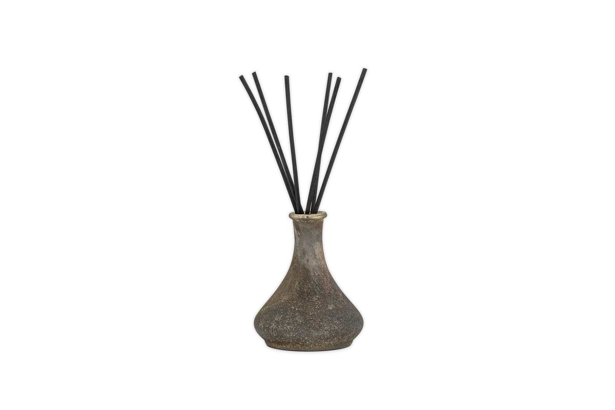 The nkuku Cedarwood & Fig Reed Diffuser features a rustic, speckled ceramic bottle with a narrow neck and black reeds, ideal for spreading a soothing cedarwood scent.