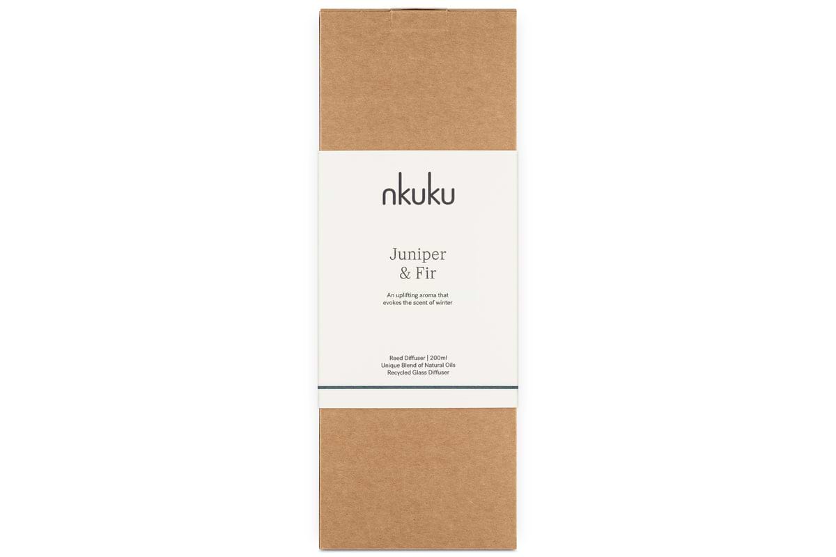 The Juniper & Fir Reed Diffuser by nkuku comes in a minimalist rectangular brown box with a central white label, displaying the brand name and scent—ideal for gifting this bespoke fragrance.