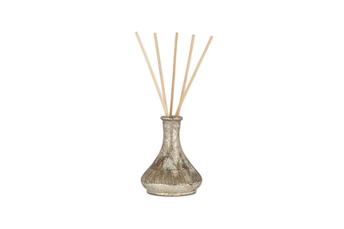 The nkuku Mandarin & Clove Reed Diffuser features a metallic, textured vase design with six light wooden reeds and fills the air with a festive spiced mandarin scent, shown against a plain white background.