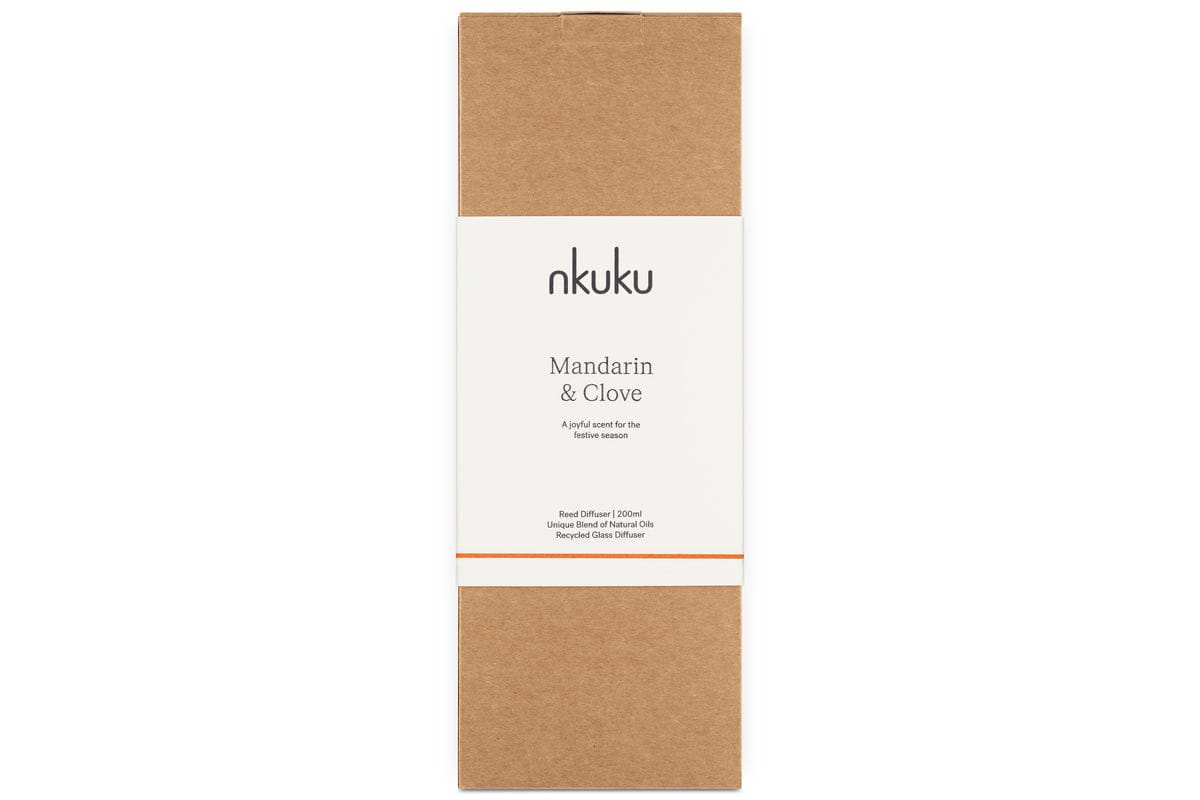 The nkuku Mandarin & Clove Reed Diffuser comes in a rectangular box with a simple brown and white design, orange accent line, and minimal text, offering a festive spiced mandarin fragrance.