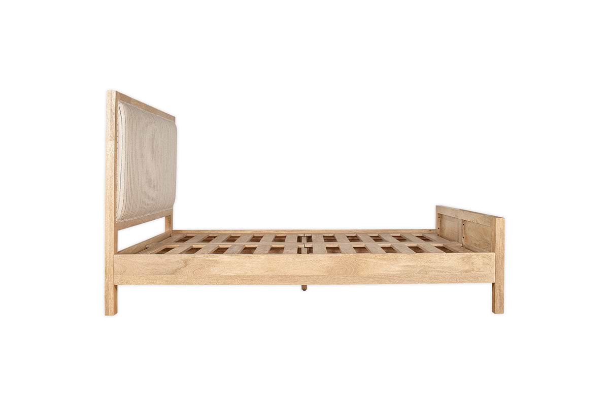 Side view of the Sanja Stripe Bed - Natural by nkuku, featuring a solid mango wood frame with slatted base, padded cotton headboard, and wooden footboard in a light finish, shown against a white background.