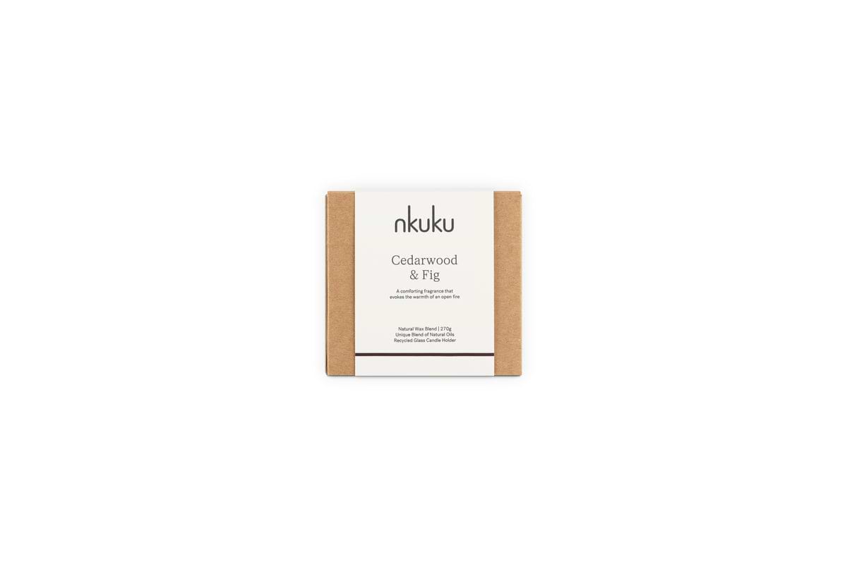 The nkuku Cedarwood & Fig 1 Wick Scented Candle, in minimalist packaging with a white label and brown kraft paper sides, fills the air with a warm honeyed fig aroma when displayed against a plain white background.