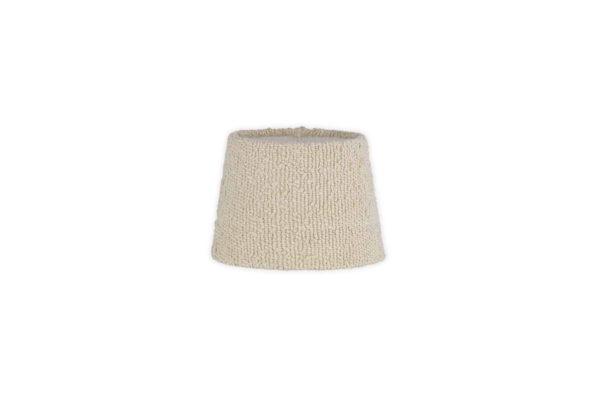 The Sakiti Bouclé Lampshade by nkuku features an off white, textured design with a gently tapered cylindrical shape. Crafted from cozy bouclé material, it adds ambient lighting to any space. The product image has a plain white background.