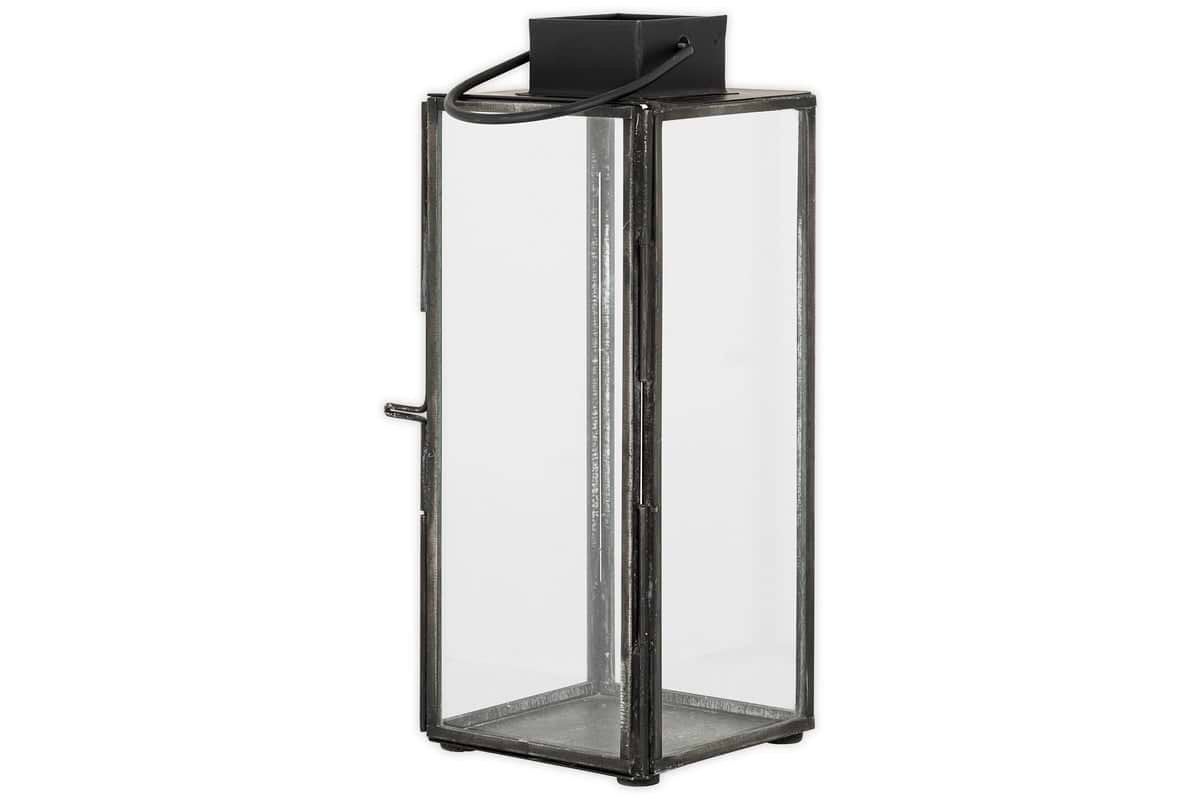 The Sia Mini Table Lantern by nkuku features a tall, rectangular black metal frame, clear glass panels, and a top handle—perfect for displaying a glowing tealight or for easy carrying and hanging.