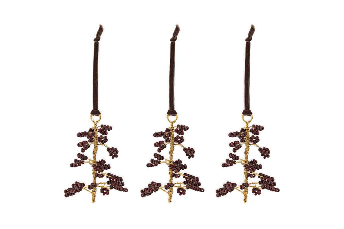 The nkuku Tanu Mango Wood Beaded Baubles - Brass & Ruby (Set of 3) feature gold stems and ruby beads, each hanging from a dark brown velvet ribbon. Unique Christmas tree decorations to brighten your festive décor.