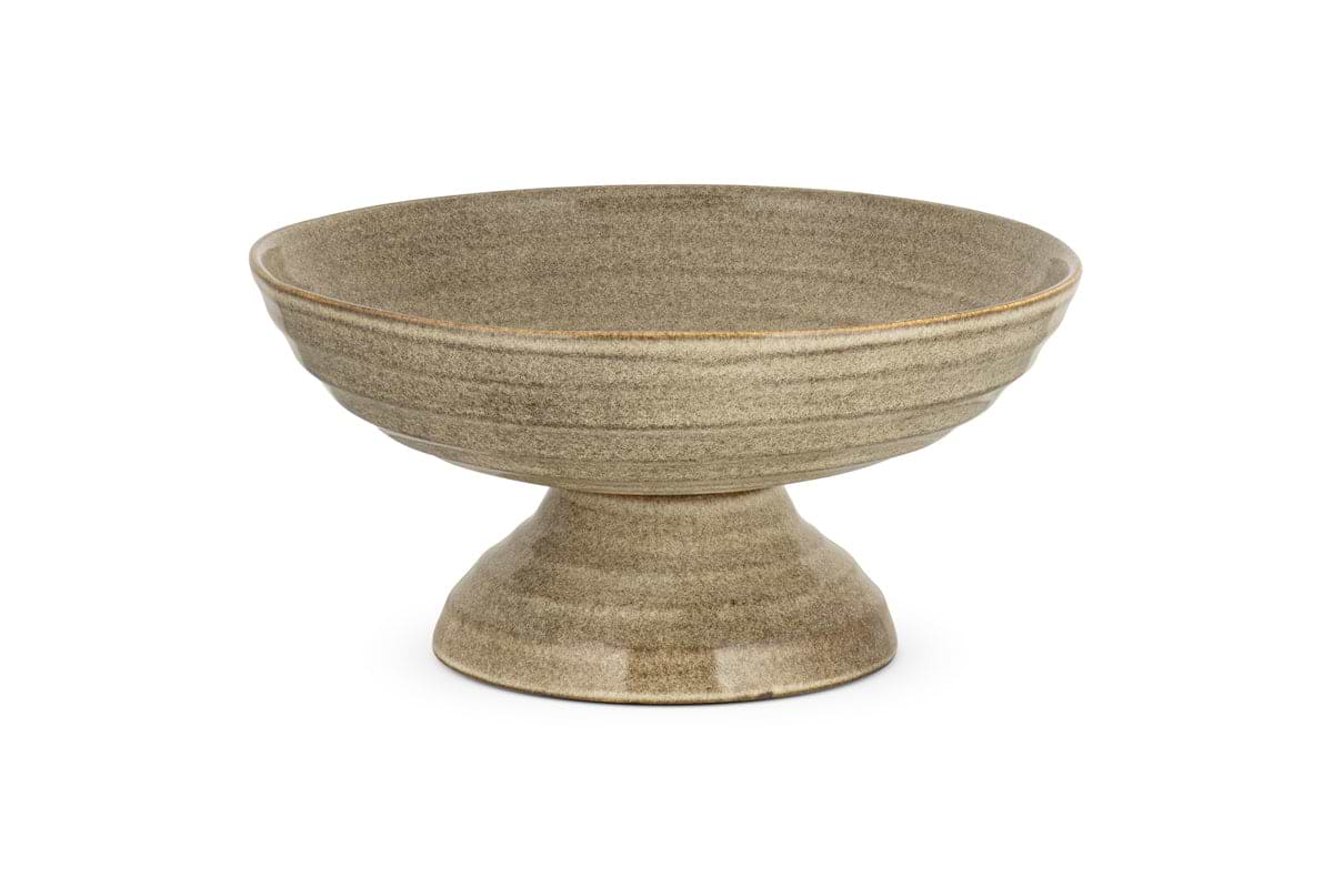 The Valinha Earthenware Footed Bowl by nkuku features a wide, shallow grey dish with a flared base and reactive glaze, ideal for enhancing rustic tablescapes. Displayed on a white background.