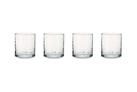 The nkuku Yala Hammered Tumbler set includes four clear, cylindrical glass tumblers with a dimpled, textured surface arranged in a row, highlighting their simple, modern design. Ideal for adding an organic touch to your tableware.