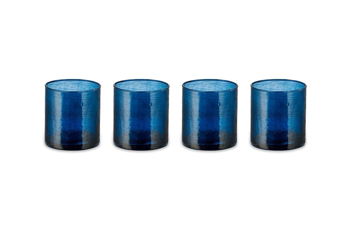 A set of four nkuku Yala Hammered Tumblers in indigo are arranged in a line on a white background. The translucent glasses feature a hammered texture and are identical in size and shape.