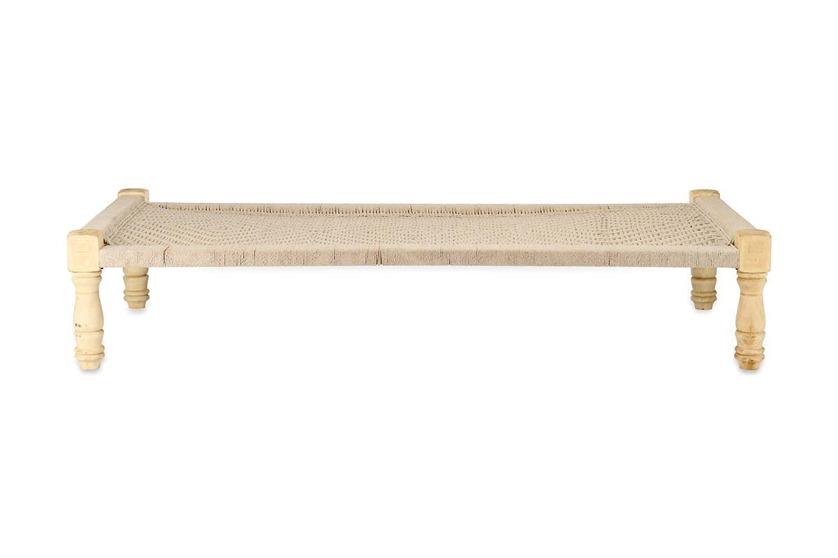 The Kutumba Mango Day Bed by nkuku features a rectangular mango wood frame, four turned legs, and a handwoven jute seat. Its light finish and rustic style showcase handmade craftsmanship, making it an ideal Indian-inspired day bed.