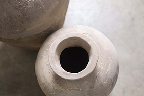 Close-up, top-down view of the nkuku Affiti Clay Tapered Pot - Large on a smooth, light surface. The wide-mouthed urn is prominent in front, with the edge of a second pot partially visible in the upper left corner.