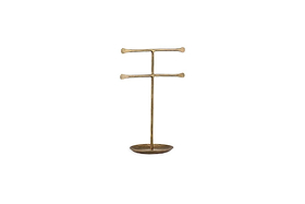 The Liman Jewellery Stand by nkuku is a minimalist brass stand with a matte finish, featuring a vertical rod and two horizontal bars for jewelry display. It has an oval base that serves as a ring tray, all set against a plain white background.
