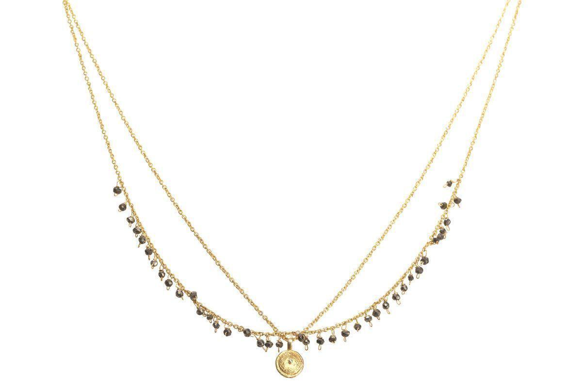 The nkuku Mai Necklace is a delicate layered gold piece with two thin chains—one featuring small pyrite stones and the other holding a round textured gold pendant.