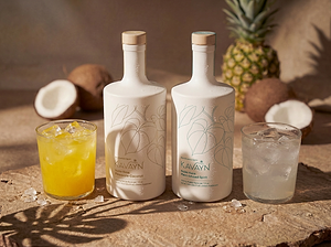 Two bottles of Kavayn gin with cocktails and tropical fruits on a wooden surface.