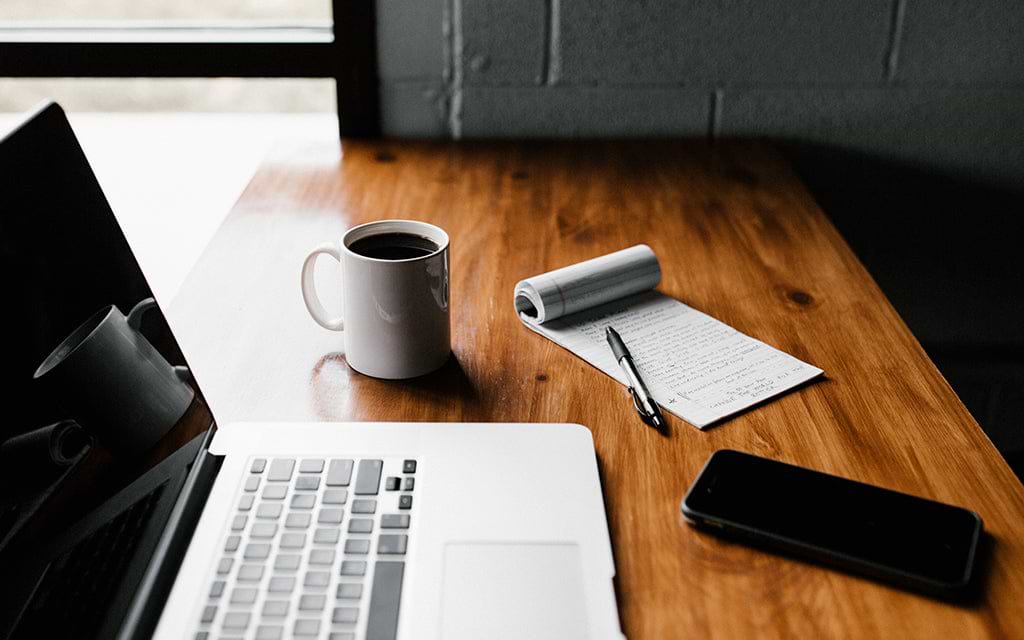 Computer, coffee cup and notebook