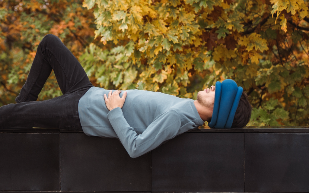 Man taking a nap wearing Light Versatile Pillow by Ostrichpillow