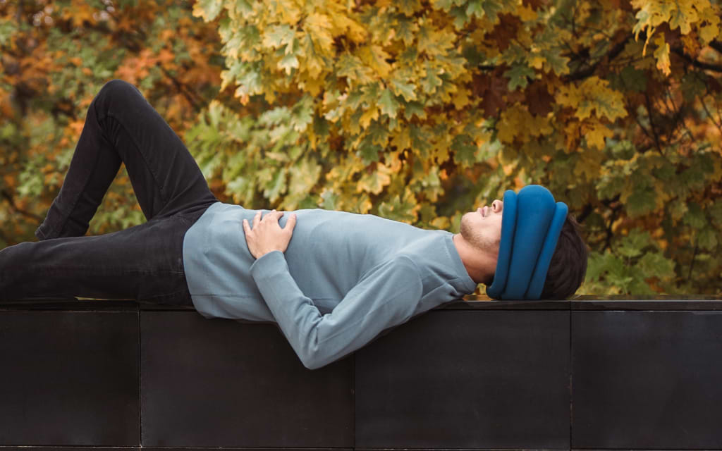 Man taking a nap wearing Light Versatile Pillow by Ostrichpillow