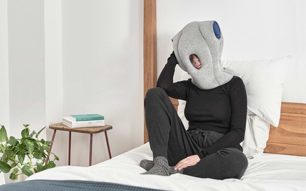 A person wearing Ostrichpillow Original Napping Pillow