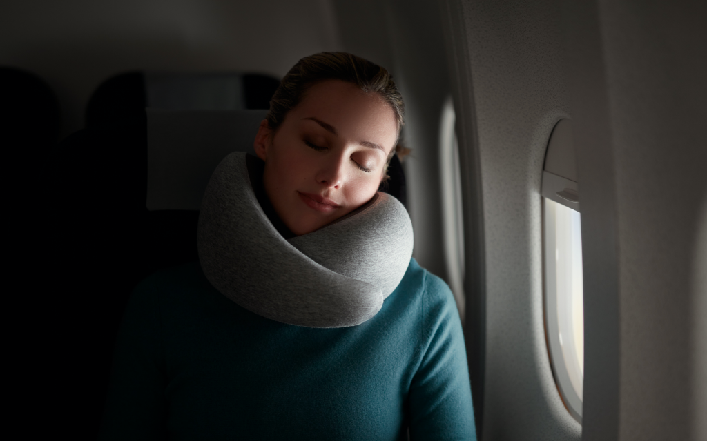 Woman sleeping on a plane using Go Neck Pillow by Ostrichpillow