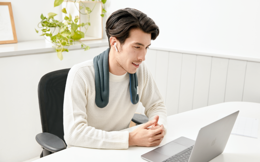 Man working with a computer and a warm compress around the neck