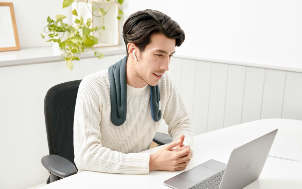 Man working with a computer and a warm compress around the neck