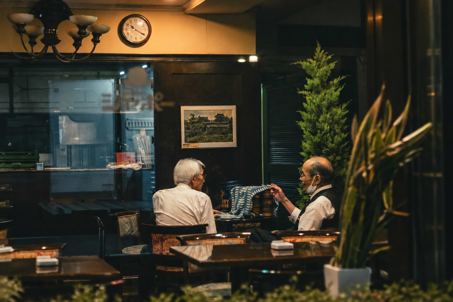 Two people talking in a café with a clock on the wall