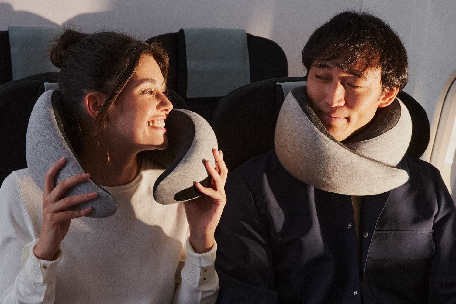 Woman adjusting Go Neck Pillow beside a man wearing one in an airplane seat.