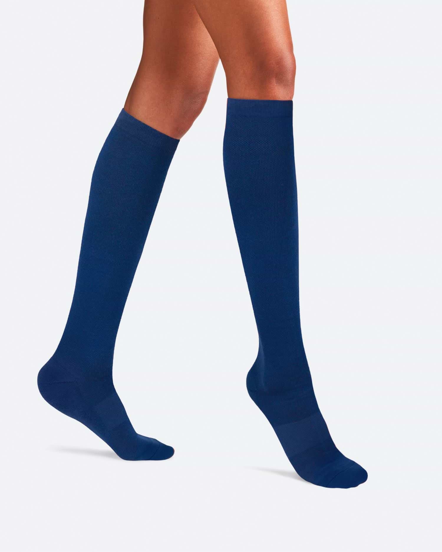 Side-profile view of a person's legs walking, wearing knee-high Ostrichpillow Bamboo Compression Socks in solid Seaside Siesta deep navy blue.