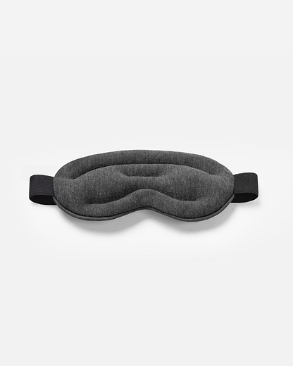 Top-down product shot of the Hot and Cold Eye Mask in Midnight Grey, showing its plush, contoured design and thick elastic strap.